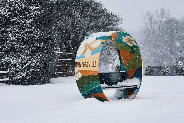 Noblewins wind turbine blade bench with Huntersville mural covered in snow in a public park